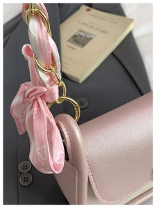 Close-up of pink pearlescent leather bag with metal ring and heart pattern scarf detail