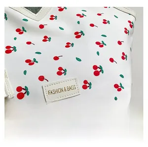 Detail of canvas tote bag with cherry print and golden FASHION & BAGS leather label