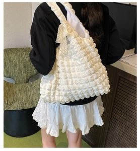 Detail of white bubble texture tote bag featuring delicate lace bow and spacious interior