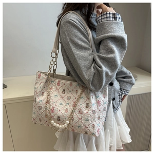 Detail of cute bear and floral print on cream tote bag with pearl chain strap