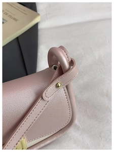 Close-up of pink leather texture and gold metal rivets on stylish crossbody bag