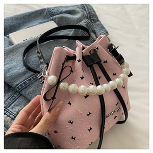 Detail of pink bucket bag with pearl handle, drawstring closure and butterfly prints