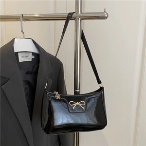 Glossy black patent leather underarm bag with a golden bow and floral zipper charm