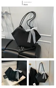 Détail du sac cabas noir avec nœud en dentelle blanche et motifs embossés en diverses scènes