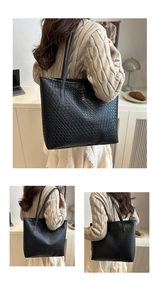 Detailed view of woven black leather texture and shoulder straps on a large tote bag