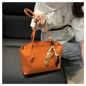 Détail du sac cabas orange à motif crocodile avec un foulard en soie décoratif au manche