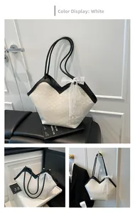 Détail du cabas en cuir blanc, bordure noire, imprimé monogramme et nœud en dentelle