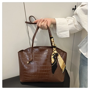 Détail du sac cabas marron foncé à motif crocodile avec un foulard en soie stylé sur l'anse