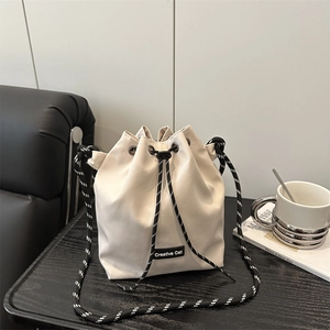 Large drawstring nylon bucket bag in cream with contrast woven shoulder strap and logo detail