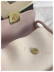 Close-up of pink leather bow bag with magnetic clasp and cat pattern lining details