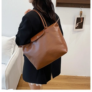 Detail view of large dark brown tote bag with leather texture and flap closure