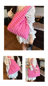 Detail of pink popcorn textured tote bag featuring a white lace bow on the strap