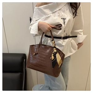 Dettaglio borsa tote marrone scuro stampa coccodrillo con manico decorato da foulard di seta