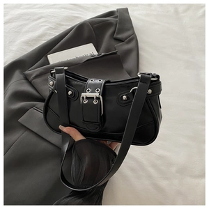Detail of silver buckles and metallic rivets on a black polished faux leather hobo bag
