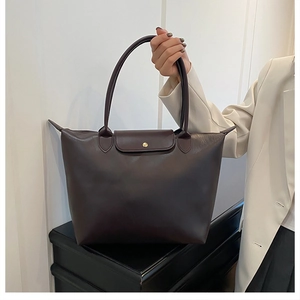 Detail of dark brown tote bag with classic leather flap and golden button closure