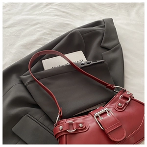 Close-up of retro dark red leather shoulder bag with vintage silver buckles and studs