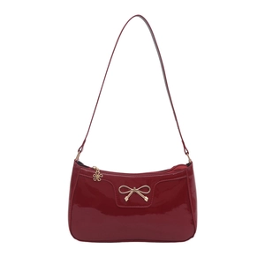 Glossy red patent leather hobo bag featuring a gold bow buckle and shoulder strap