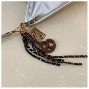 Détail du pendentif de sac avec mini boulier doré et bretzel sur un sac en cuir chic