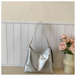 Détail du sac sous le bras argenté métallisé avec foulard et boucles en laiton