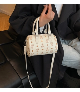 Detail view of cream Boston bag with brown bear prints and silver hardware details