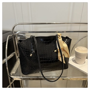 Détail du sac cabas noir motif crocodile avec foulard décoratif sur présentoir
