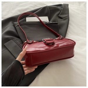 Detail of dark red faux leather texture and silver buckle on vintage shoulder bag