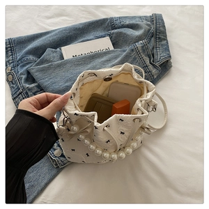 Close-up of white pleated bucket bag with bow print showing interior storage capacity