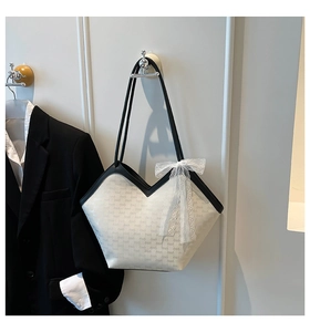 Détail du sac fourre-tout ivoire avec bordure noire et nœud décoratif en dentelle
