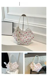 Detail of white tote bag with red cherry print and branded wide shoulder strap