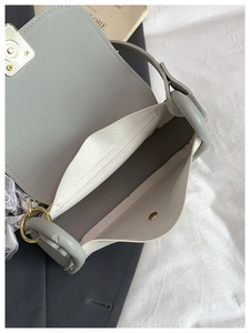 Detail view of grey leather bag interior with white fabric pocket and floral silk scarf charm