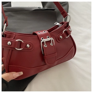 Detailed macro view of dark red matte leather bag with silver buckles and rivets