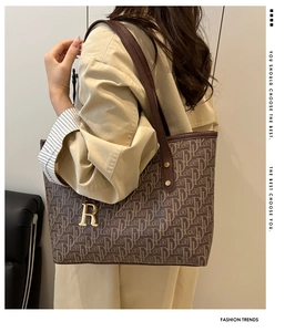 Détail d'un grand sac cabas marron avec logo monogramme et pendentif doré lettre R
