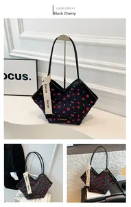 Detail of black cherry print tote bag with woven strap and fashion brand logo detail