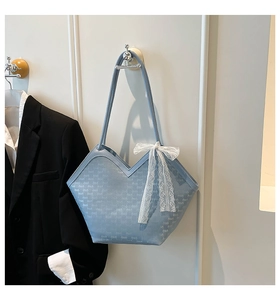 Détail d'un sac cabas bleu clair avec ouverture en V et nœud en dentelle blanche chic