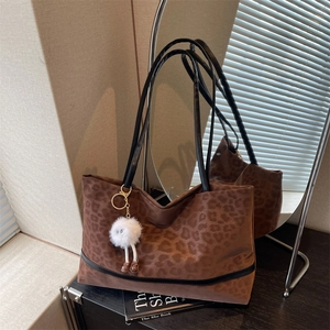 Brown leopard print oversized tote bag with black leather handles and plush charm