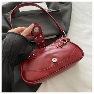 Close-up of red underarm bag with silver studs and magnetic buckle on grey blazer