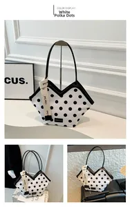 Detail of white tote bag with black polka dots featuring branded wide shoulder strap