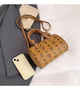 Detailed view of mini brown barrel bag with bear print and phone for size reference