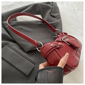 Close-up of red hobo bag featuring metallic rivets and buckle straps in Y2K aesthetic style