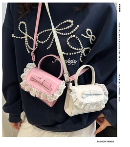 Detail of pink and white mini lace crossbody bags with bow accent and PU leather texture