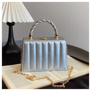 Close-up of a silver box handbag with wave texture and metallic spiral top handle