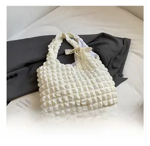 Close-up of white bubble puff tote bag featuring an elegant lace bow on the shoulder strap