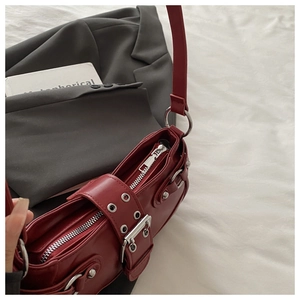 Detail of burgundy matte leather bag with silver buckle strap and zip closure