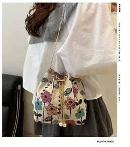 Detailed view of bucket bag featuring colorful floral jacquard with pearl drawstring charms
