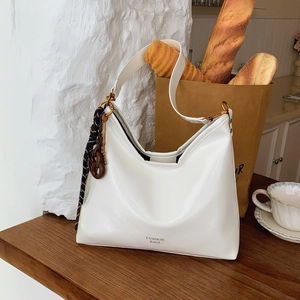Sac hobo blanc minimaliste avec foulard en soie et finitions dorées sur table en bois