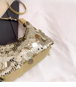 Close-up of golden sequins on women underarm bag with soft khaki leather details
