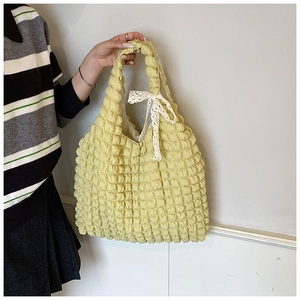 Detail of yellow waffle texture fabric handbag with elegant white lace bow decoration
