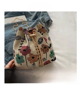 Detail of vintage floral jacquard bucket bag featuring gold chain and pearl drawstring