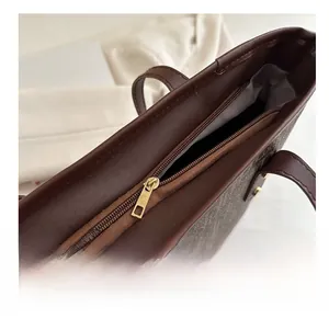 Détail de la fermeture éclair dorée sur un grand sac cabas à motif monogramme marron