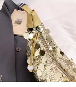 Detail of smooth gold sequin texture and leather zipper pull with white bead charms